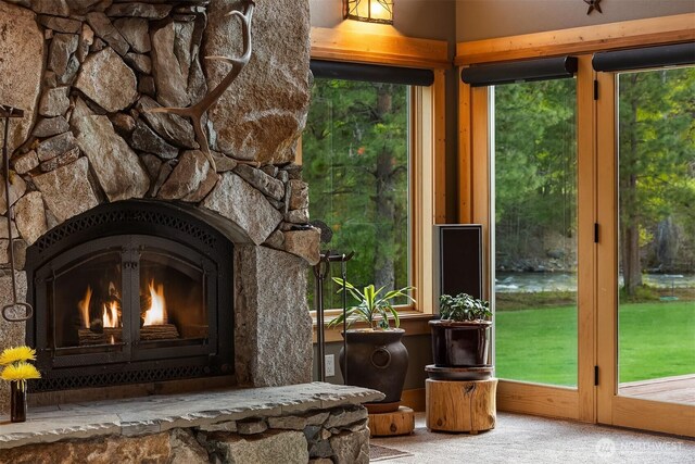 living area with carpet flooring and a stone fireplace