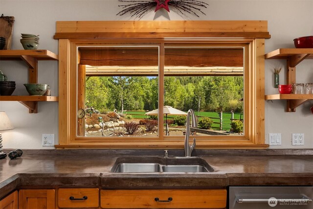 kitchen with open shelves, dark countertops, a sink, and stainless steel dishwasher