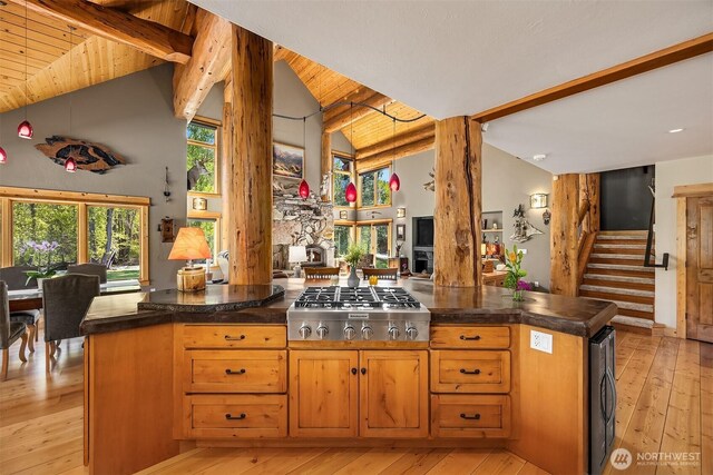 kitchen featuring stainless steel gas stovetop, light wood finished floors, open floor plan, ornate columns, and wine cooler