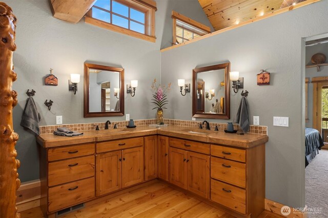 full bathroom with wood finished floors, connected bathroom, double vanity, and high vaulted ceiling