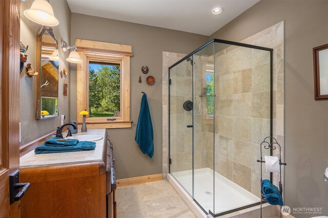 bathroom featuring a stall shower, baseboards, and vanity