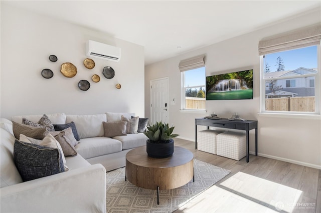 living room featuring a wall unit AC, healthy amount of natural light, wood finished floors, and baseboards