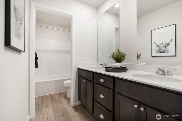 full bath with toilet, wood finished floors, double vanity, and shower / washtub combination
