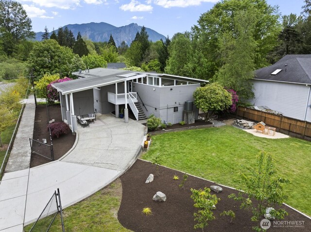 view of front of property featuring a patio, stairway, concrete driveway, a mountain view, and a fire pit