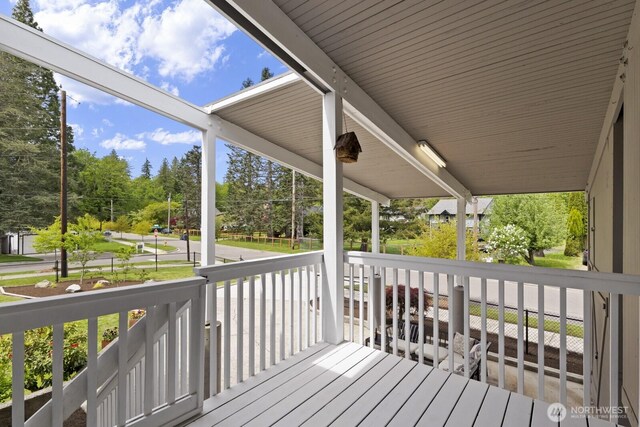 wooden deck with view of scattered trees and a porch