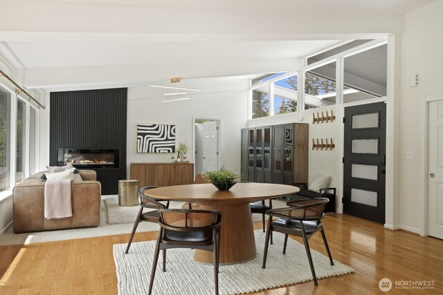 dining space featuring light wood-style flooring, baseboards, and a large fireplace