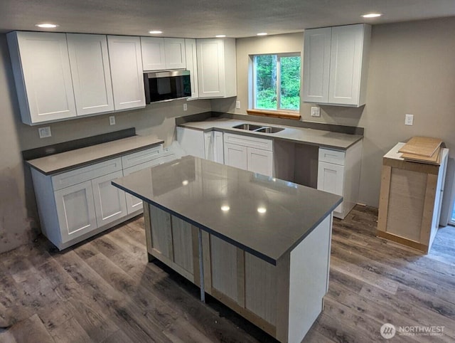 244 Skate Creek Rd N, Ashford, WA 98328 - kitchen with stainless steel microwave, wood finished floors, white cabinets, recessed lighting, and a kitchen island