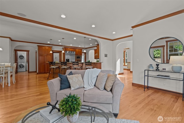 13514 95th Ave NE, Arlington, WA 98223 - living area featuring arched walkways, stacked washing machine and dryer, light wood-style floors, ornamental molding, and baseboards