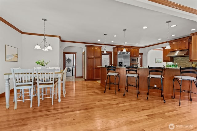 13514 95th Ave NE, Arlington, WA 98223 - dining area featuring arched walkways, stacked washer / drying machine, light wood-type flooring, crown molding, and recessed lighting