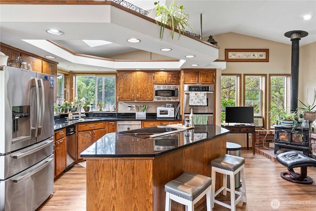 2219 W Pioneer Ave, Puyallup, WA 98371 - kitchen featuring stainless steel appliances, a wood stove, a sink, brown cabinetry, and light wood-style flooring
