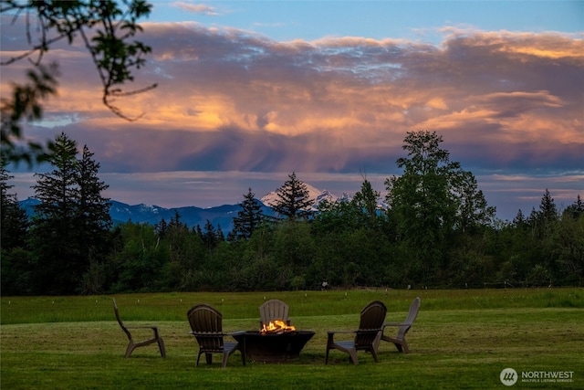 view of community with a fire pit, a lawn, and a mountain view
