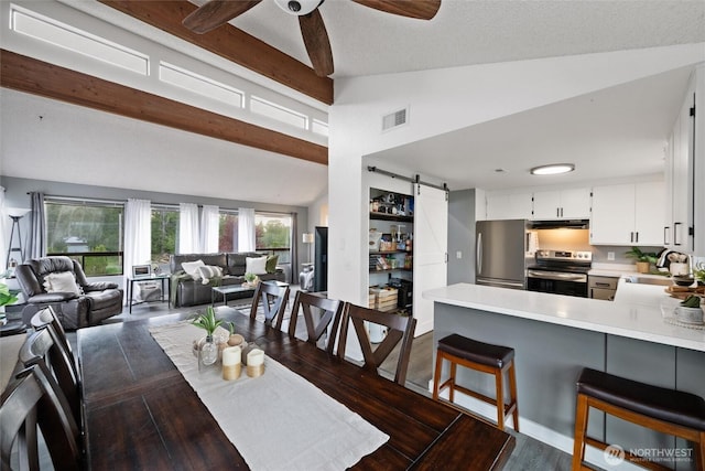 dining room featuring a barn door, a ceiling fan, and dark wood-style floors