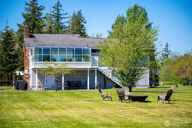 rear view of house with stairs, a chimney, a lawn, and a wooden deck
