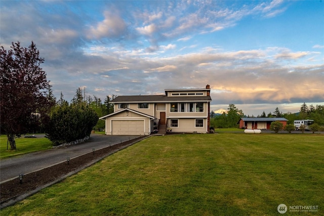 traditional-style home featuring asphalt driveway, a front lawn, and an attached garage