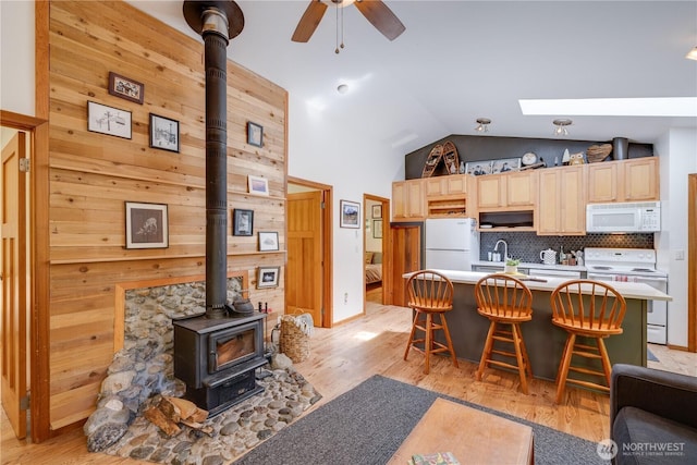 7537 Canyon View Dr, Glacier, WA 98244 - living room with a wood stove, lofted ceiling, light wood finished floors, a ceiling fan, and a skylight