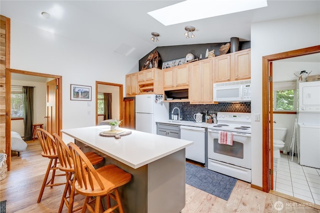 7537 Canyon View Dr, Glacier, WA 98244 - kitchen featuring white appliances, stacked washer / dryer, a skylight, a sink, and a breakfast bar