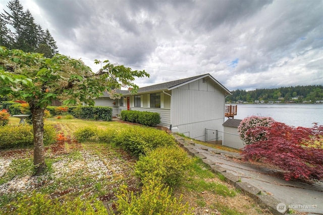view of side of home with fence and a water view