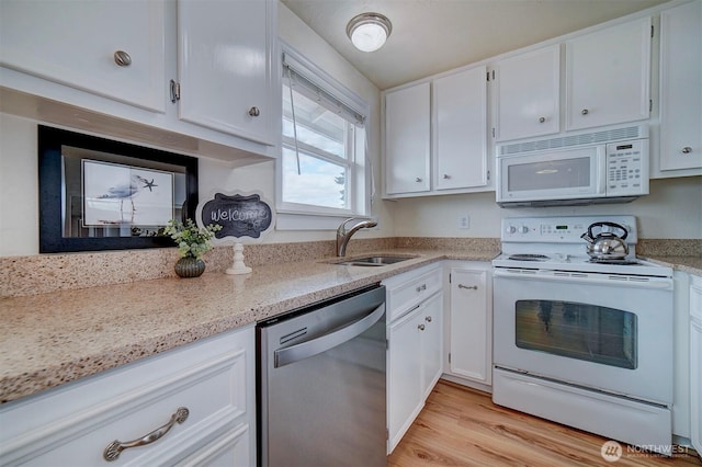 kitchen featuring white appliances, a sink, white cabinets, and light stone counters