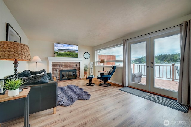 living area with wood finished floors, a fireplace, french doors, and baseboards
