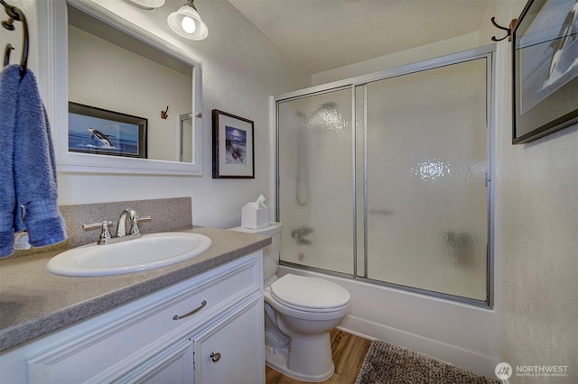 full bathroom featuring vanity, enclosed tub / shower combo, toilet, and wood finished floors