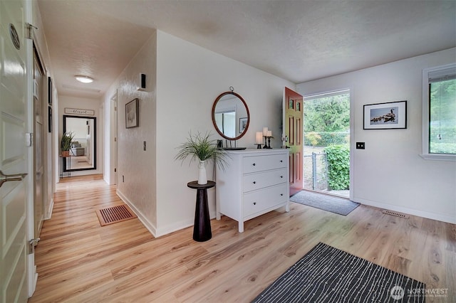 foyer entrance with light wood-style flooring and baseboards