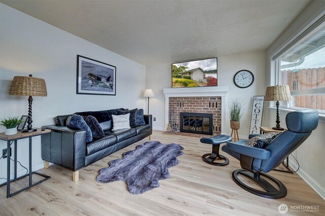 living room with wood finished floors, baseboards, and a brick fireplace