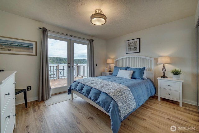 bedroom featuring access to outside, french doors, light wood-style flooring, baseboards, and a textured ceiling