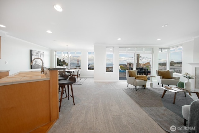 living area with light carpet, ornamental molding, a chandelier, and recessed lighting
