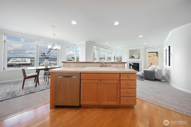 kitchen with tile counters, stainless steel dishwasher, a sink, a chandelier, and open floor plan