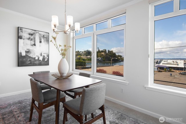 dining space featuring ornamental molding, a chandelier, baseboards, and carpet