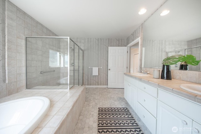bathroom featuring a stall shower, a garden tub, double vanity, recessed lighting, and tile patterned floors