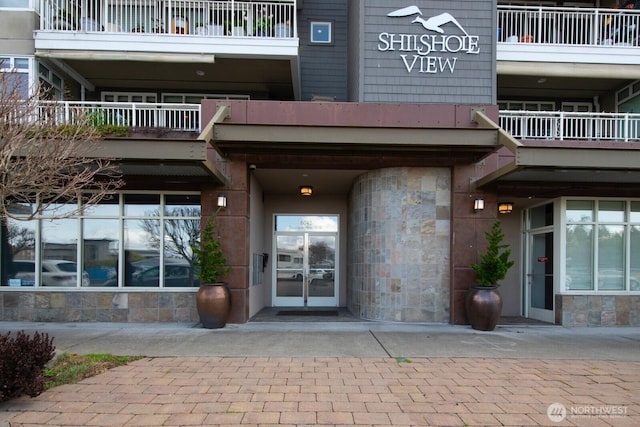 property entrance featuring stone siding and a balcony