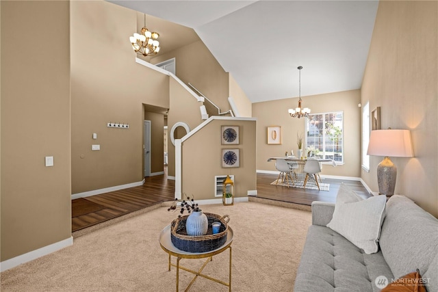 carpeted living room with a chandelier, high vaulted ceiling, and baseboards