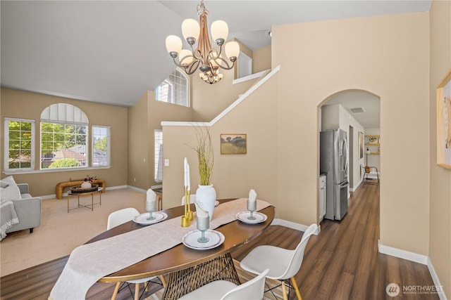 dining space featuring a chandelier, plenty of natural light, baseboards, and a towering ceiling