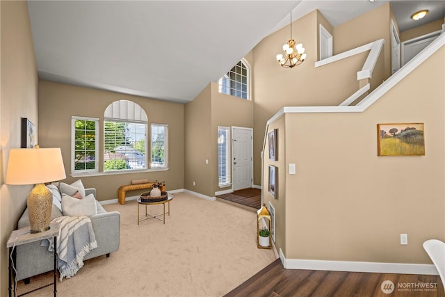 foyer entrance featuring baseboards, a chandelier, and a towering ceiling