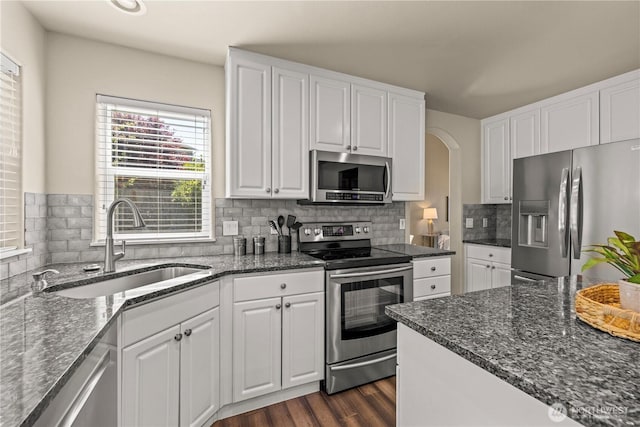 kitchen with appliances with stainless steel finishes, a sink, white cabinets, dark wood-type flooring, and recessed lighting