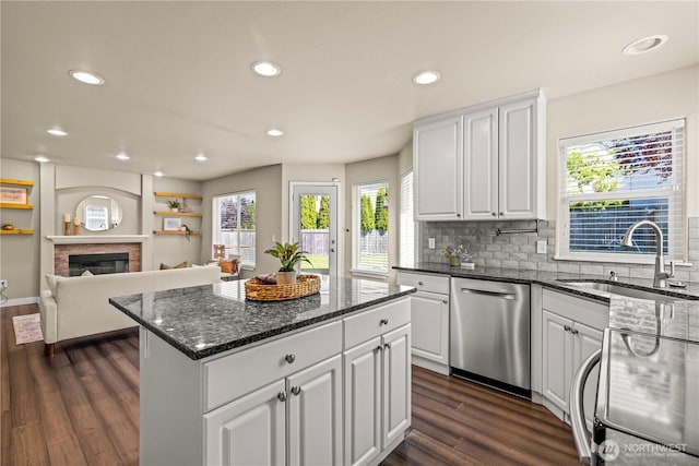 kitchen with stainless steel dishwasher, a sink, dark wood-type flooring, white cabinets, and recessed lighting