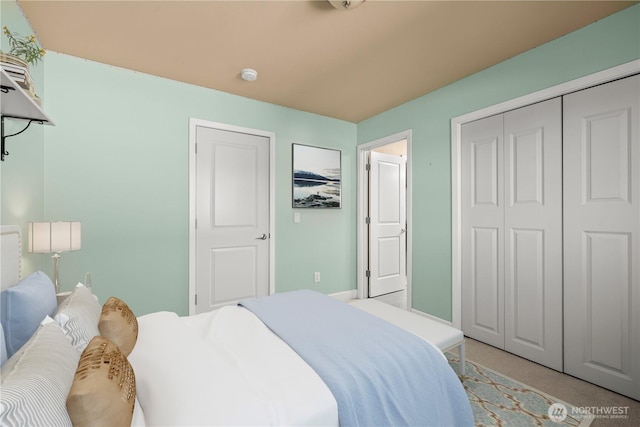 bedroom featuring light carpet, a closet, and baseboards
