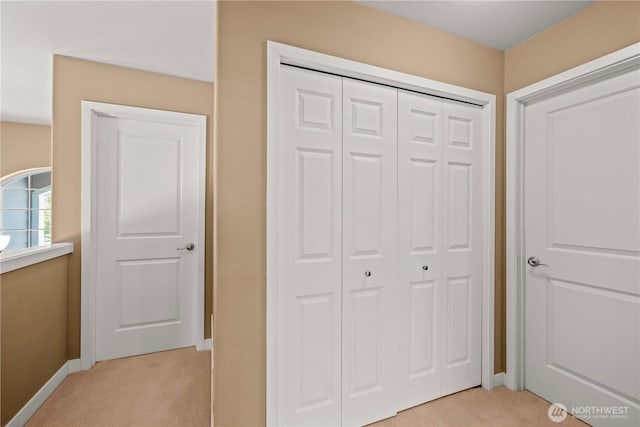 unfurnished bedroom with light colored carpet, a closet, and baseboards