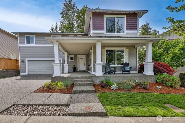 view of front of house featuring covered porch, driveway, a garage, and fence