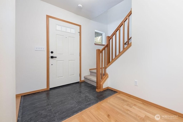 foyer entrance with stairs, baseboards, and dark wood-style flooring