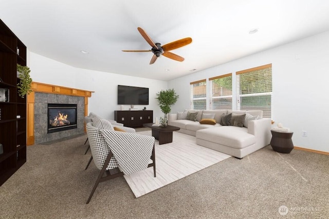living area with a tile fireplace, carpet flooring, a ceiling fan, and baseboards