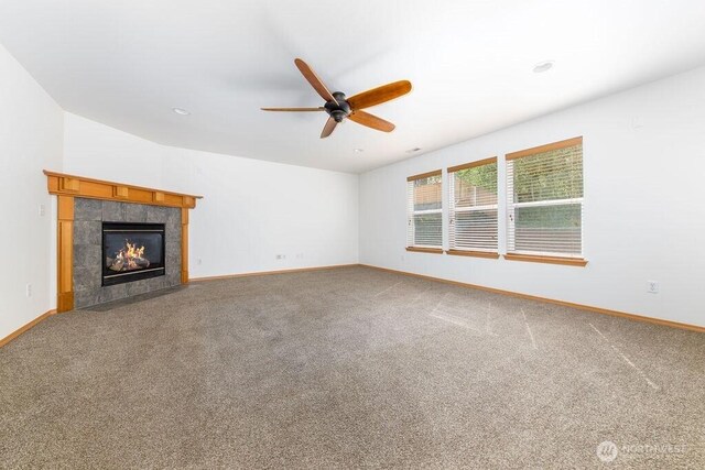 unfurnished living room featuring ceiling fan, baseboards, a fireplace, and carpet