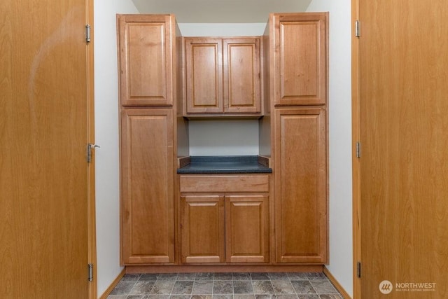 kitchen with dark countertops, baseboards, and brown cabinetry