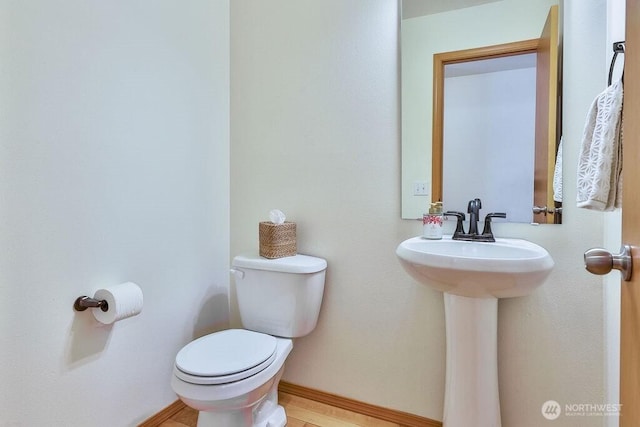 bathroom featuring toilet, a sink, and baseboards