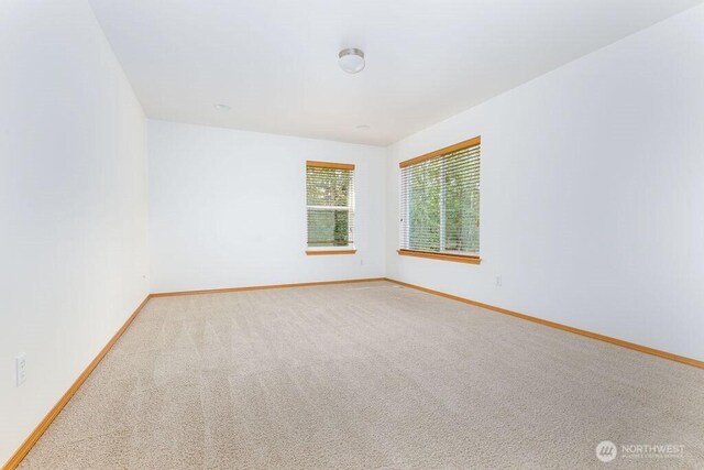 carpeted spare room featuring baseboards