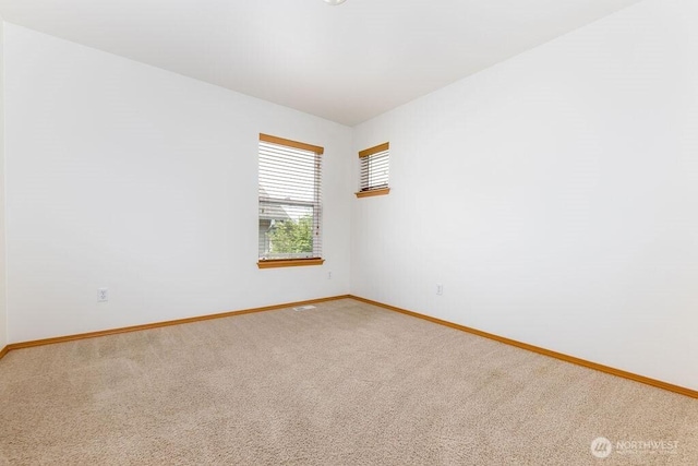 unfurnished room with baseboards and light colored carpet