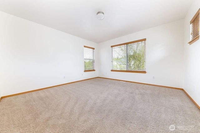 unfurnished room featuring baseboards and light colored carpet