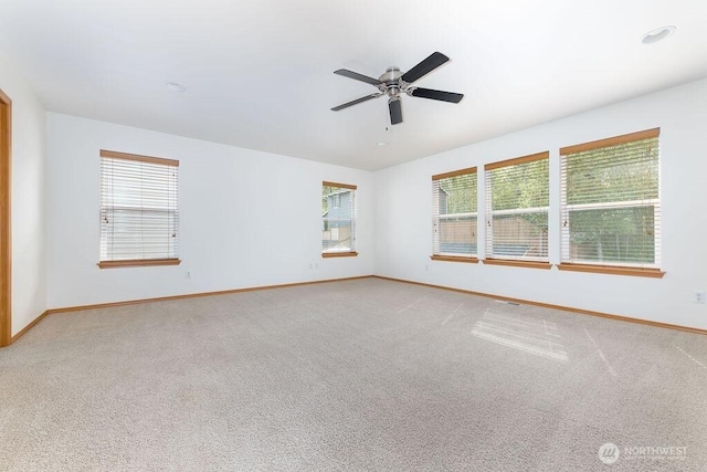 spare room with light colored carpet, baseboards, and plenty of natural light