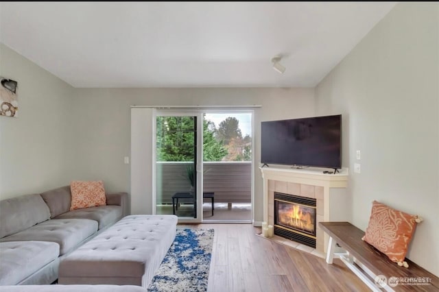 living room with wood finished floors and a tile fireplace